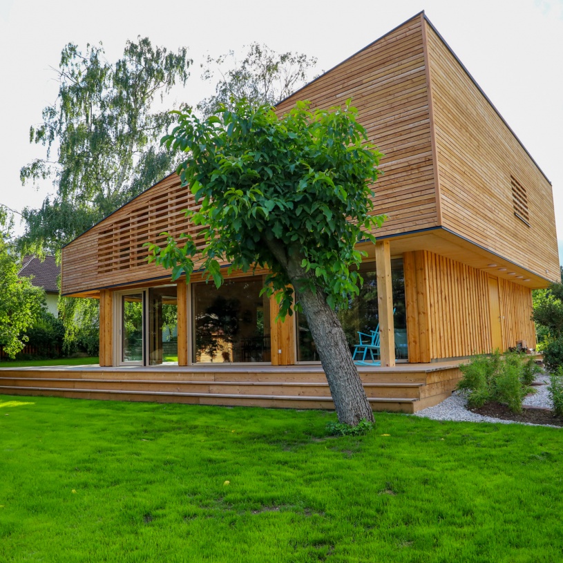 Große Holzterrasse mit Kieselgarten rechts und einem kleinen Baum davor