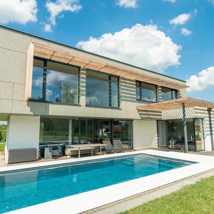 Ein modernes zweistöckiges Haus mit vorgesetzten Lamellen und einem großen Pool