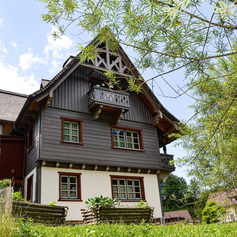 Wohnhaus mit hölzernem oberem Stockwerk mitten im Grünen leicht von unten abfotografiert