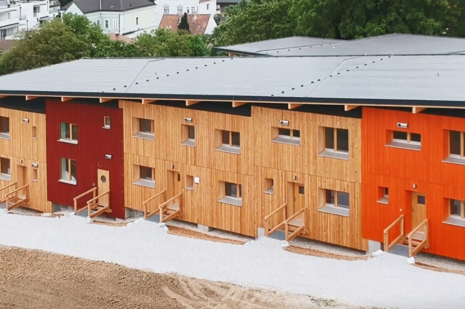 Ein großes Wohnhaus mit 3 Holzfassaden, einer roten und einer orangen Fassade