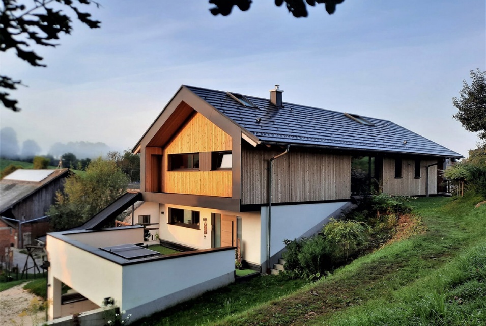 Außenansicht eines modernen Eingangsbereichs eines weißen Hauses mit holzverkleidetem Obergeschoss