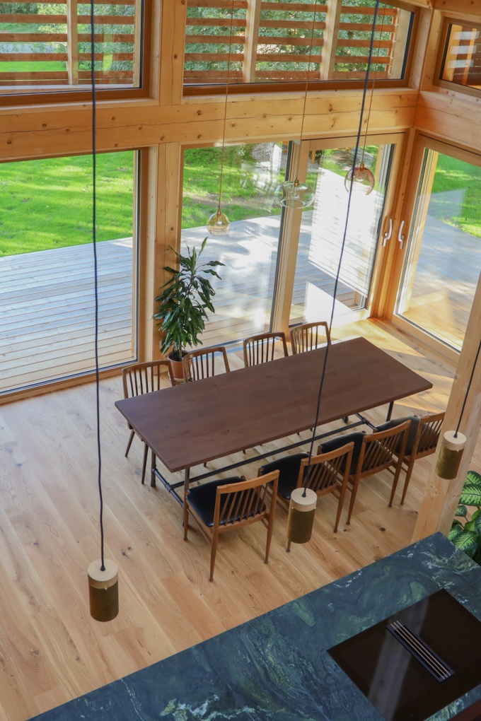Ein Wohnzimmer aus Vogelperspektive mit einem langen Holztisch und einem Teil der Küchenarbeitsplatte