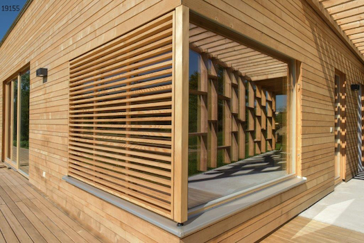 Ansicht eines halbseitig mit Holz verkleidetem großen Fenster inmitten einer Holzfassade