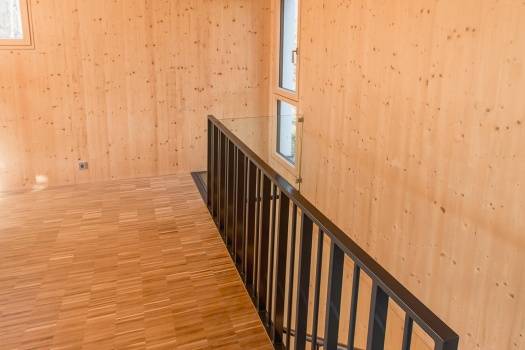 Ein Fußboden aus Holz, Wände und Decken aus Holz und eine Treppe die nach unten führt auf der rechten Seite