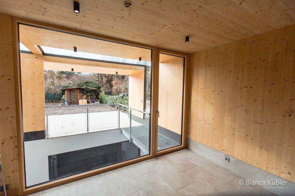 Eine große Glastür mit Blick auf eine Holzhütte und Wände und Decke aus hellem Holz