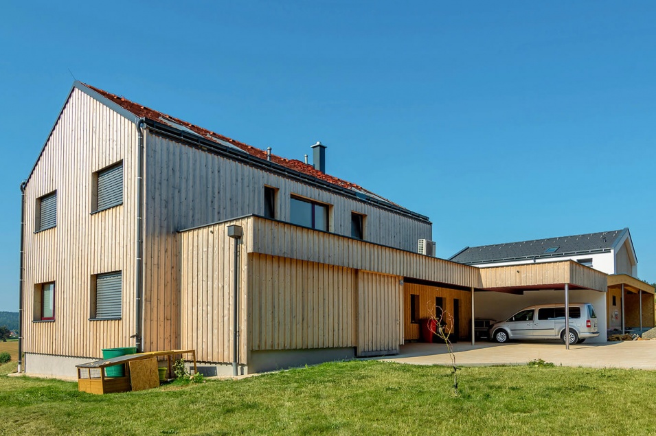 Ein Haus mit senkrechten Holzfassaden und einem Garten davor.