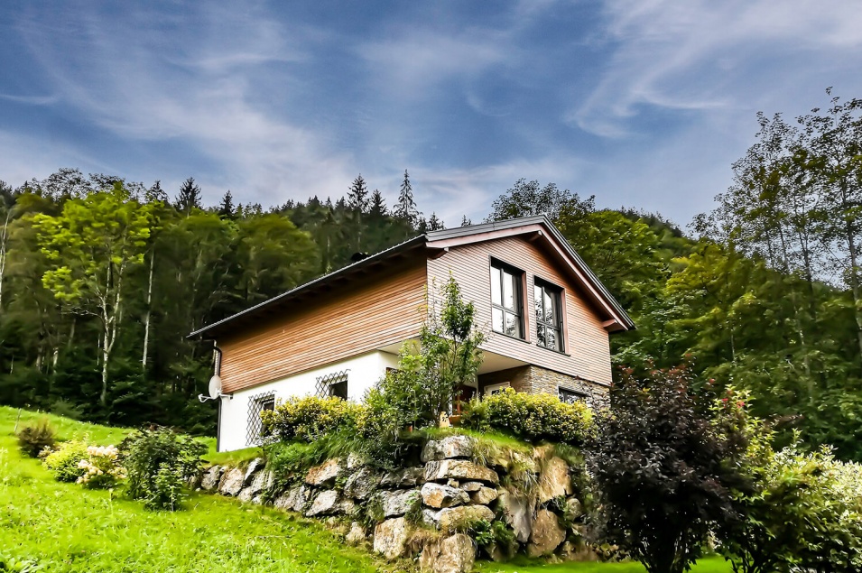 Wohnhaus mit hölzernem oberem Stockwerk auf einem bewaldeten Berg