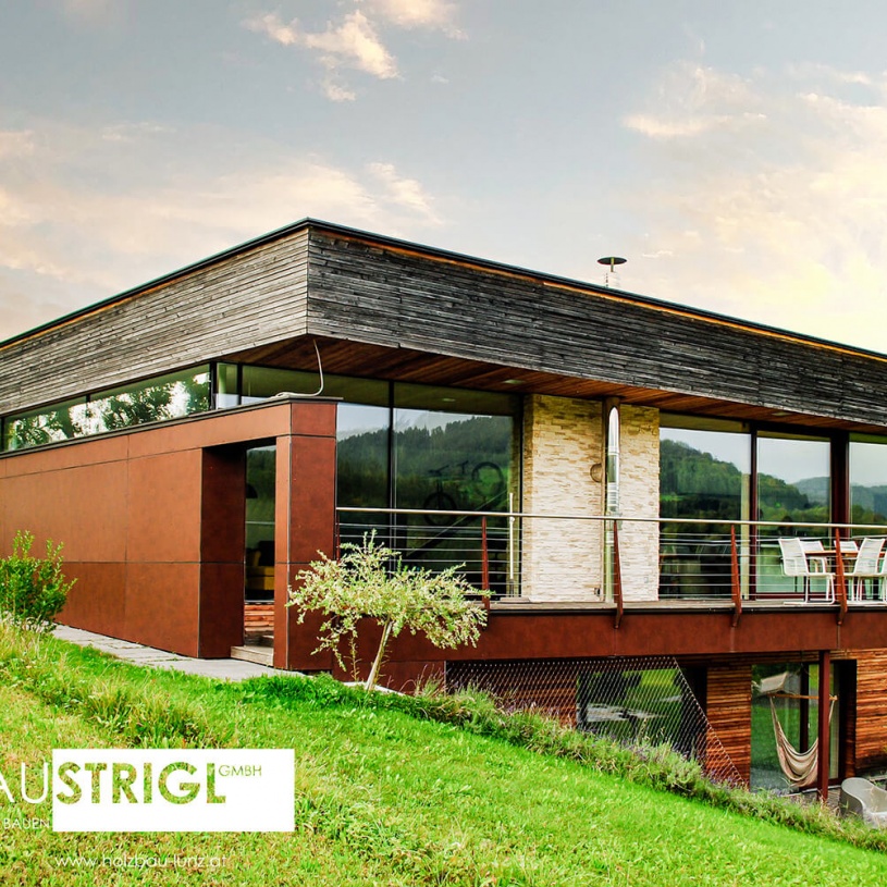 Ein zweistöckiges Haus aus ausgeblichenem Holz mit einem Garten und einem Balkon im zweiten Stock