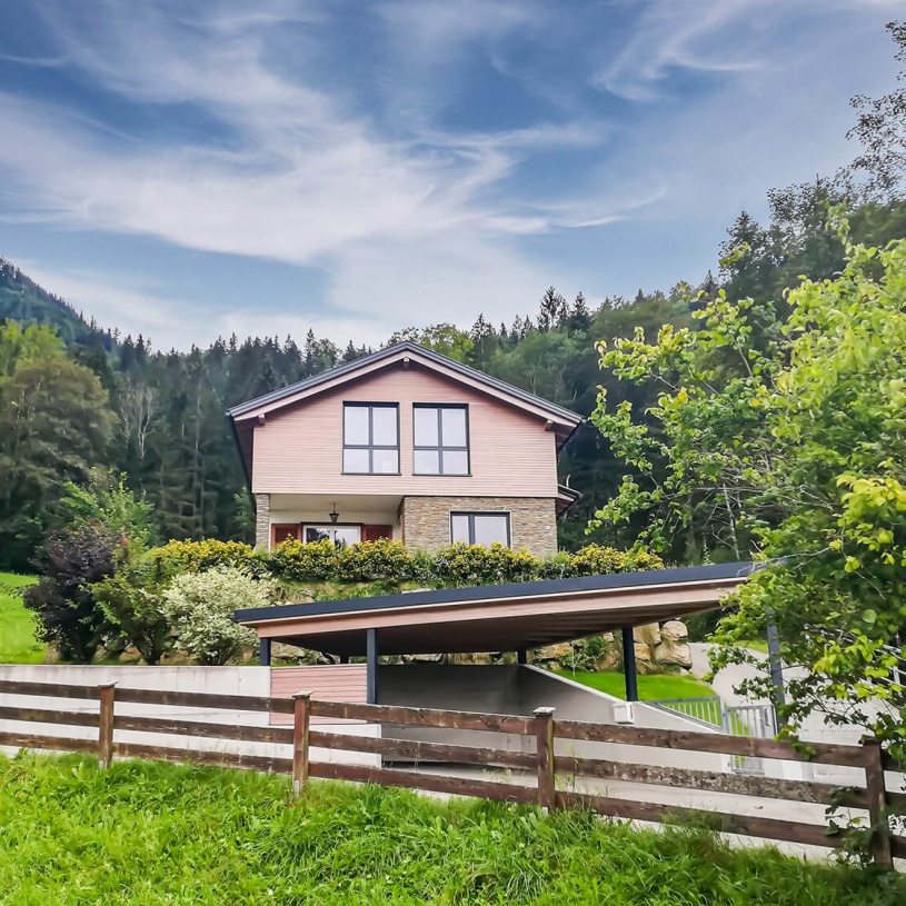 Wohnhaus mit hölzernem oberem Stockwerk auf einem bewaldeten Berg mit Garage von unten