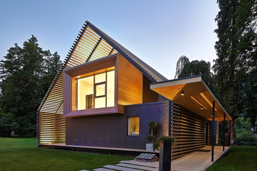 Ein großes Passivhaus aus Holz mit großem Fenster im ersten Stock und Teil eines Gartens