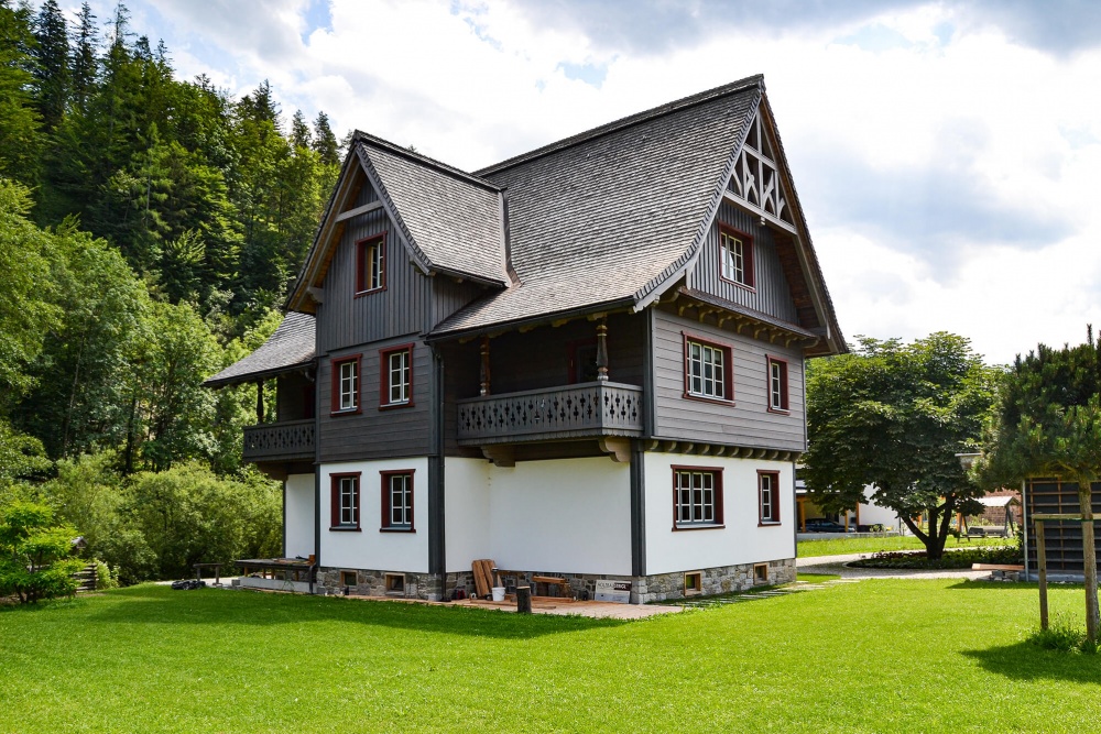 Frontalansicht eines revitalisierten Holzhause mit Wiese im Vordergrund