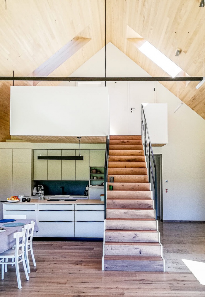Eine Holztreppe inmitten eines offenen und hellen Raumes in einem Holzhaus|holzhaus-treppe-im-raum